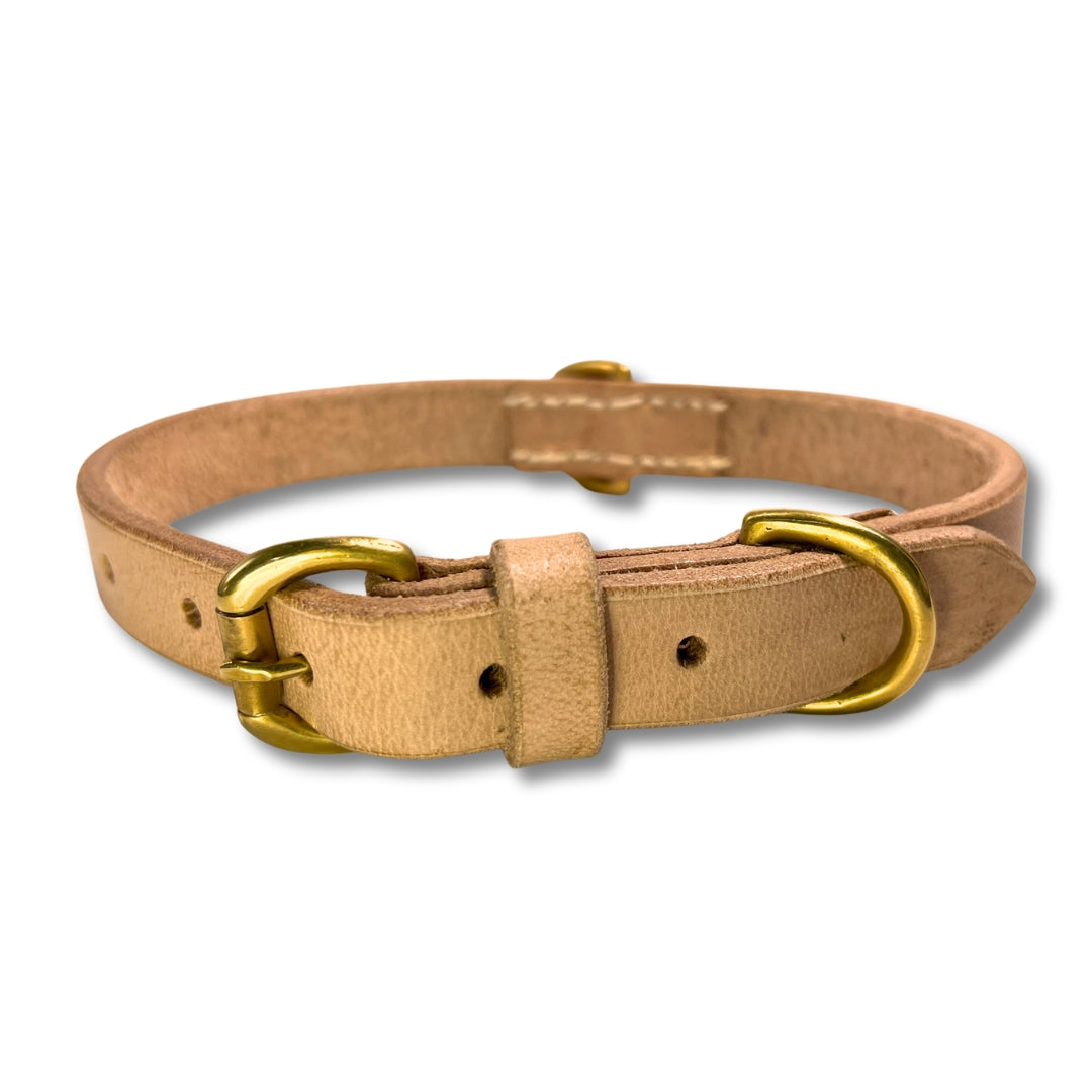 A Bald Collar Raw by Georgie Paws, made of tan buffalo leather with a brass buckle and loop, isolated against a white background.