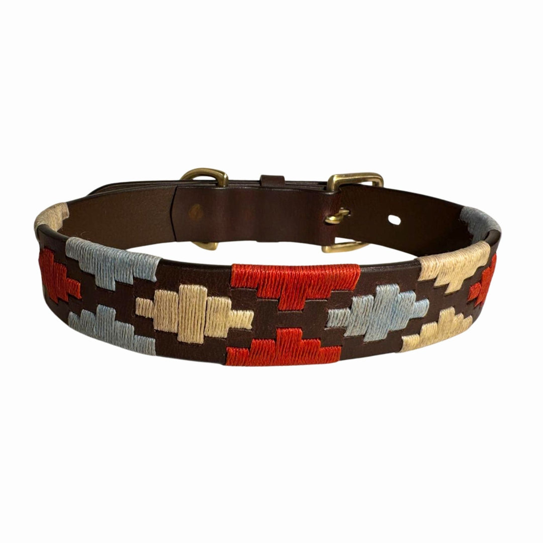 The Polo Collar - Claude by Georgie Paws is a brown waxed buffalo leather collar with a gold buckle, decorated with red, beige, and light blue geometric embroidery in repeating block-shaped patterns around the collar.