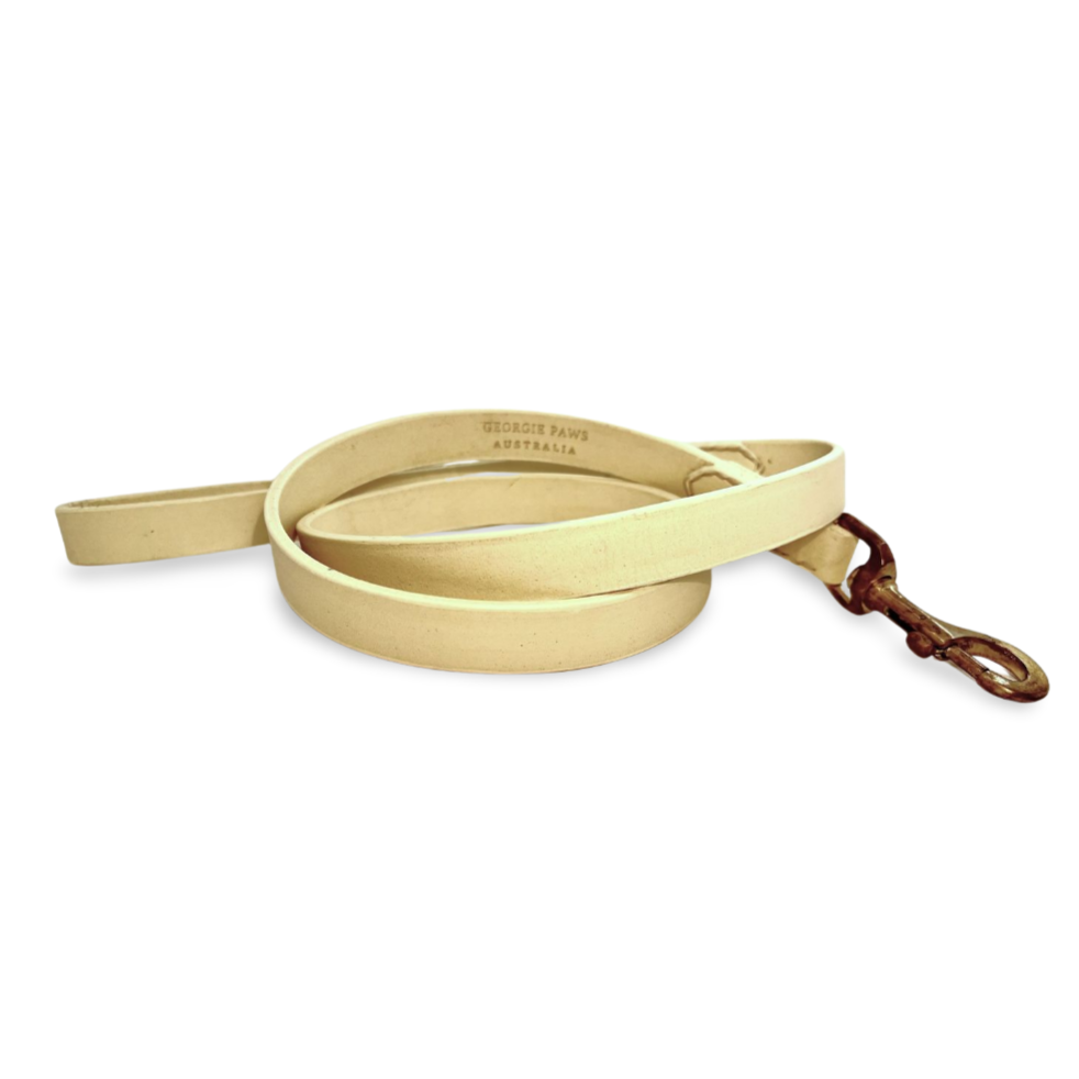 A rolled-up, light tan Georgie Paws buffalo leather dog leash with a brass swivel hook, featuring a stamped label indicating Australian origin, isolated on a white background.