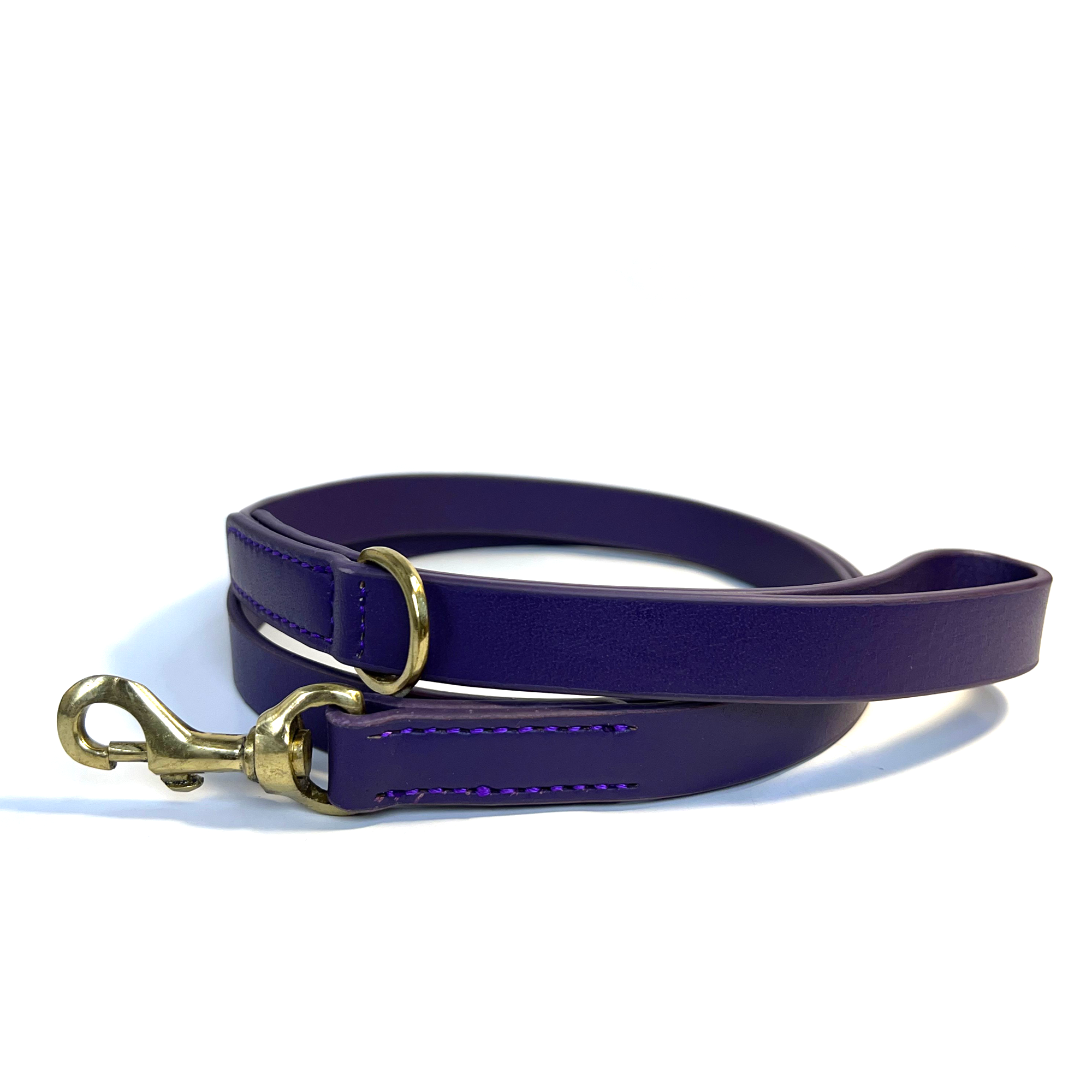 A Bald Lead Purple leather dog leash with antique brass hardware and stitching, coiled against a white background, designed for walking pets by Georgie Paws.