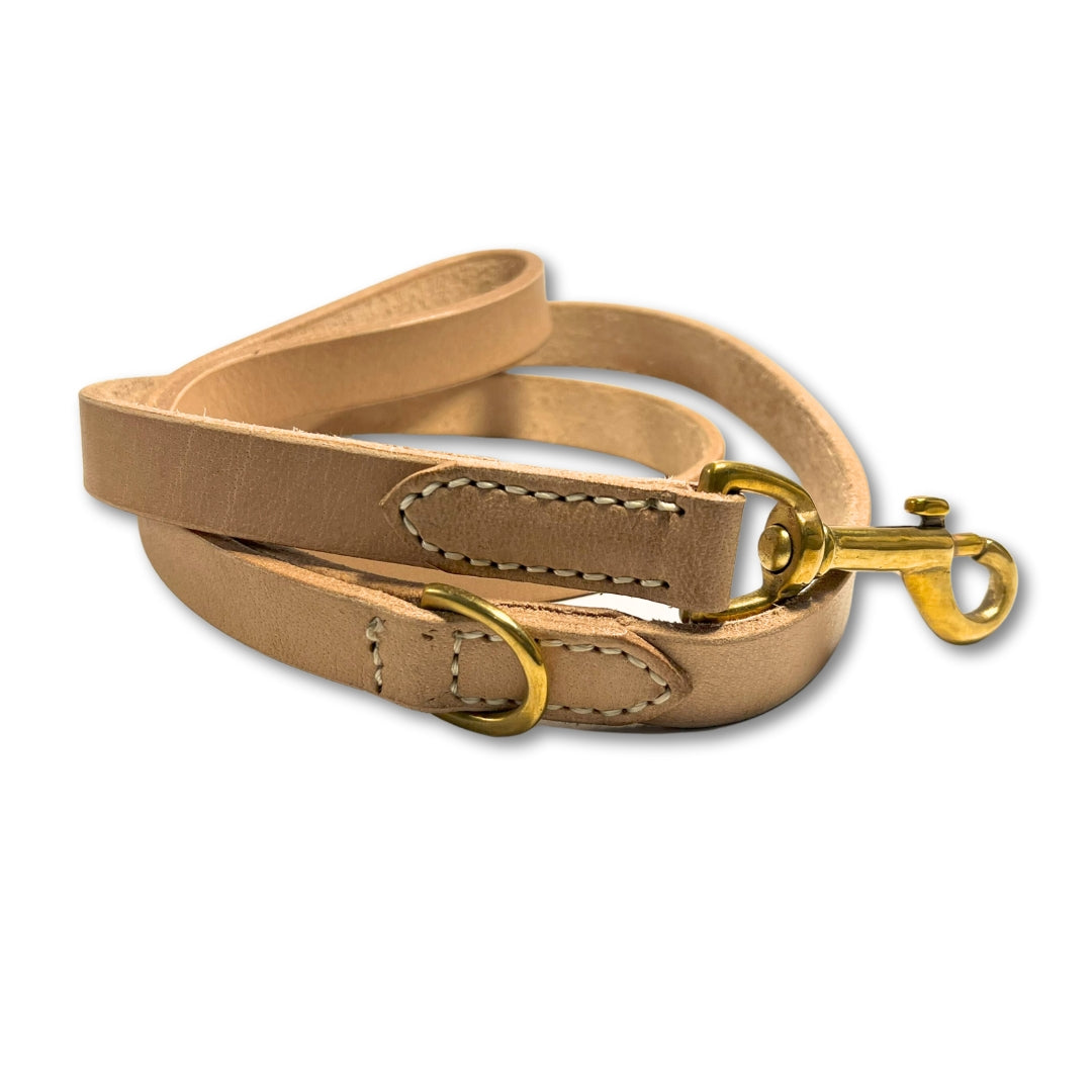 A Bald Lead Raw dog leash by Georgie Paws, made of tan buffalo leather with golden brass hardware, displaying neat stitching and a loop handle, isolated on a white background.