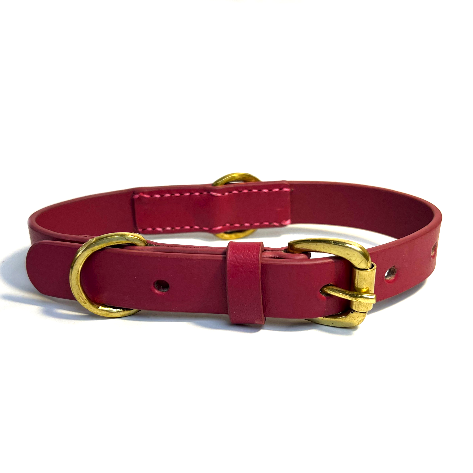 A hand-made Georgie Paws Bald Collar Ruby with gold-tone hardware, featuring a buckle closure and d-ring attachment point, isolated against a white background.