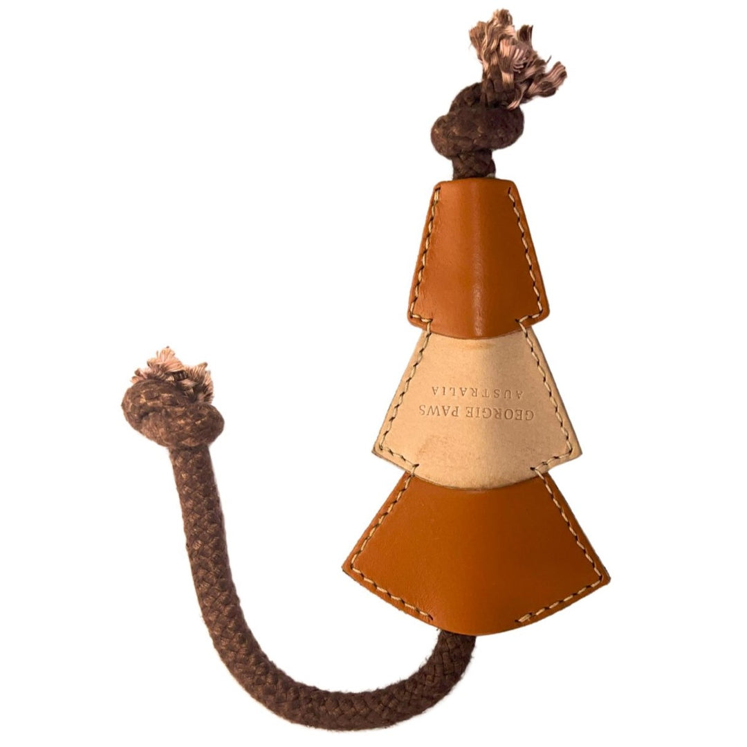 Introducing the Bush Christmas Chew Toy - ochre from Georgie Paws, a delightful leather dog toy shaped like a Christmas tree. Made from eco-friendly, veg-tanned buffalo leather, it comes in an earthy ochre color with three tiers connected to knotted brown rope for durability and easy gripping. The middle tier features debossed text, while frayed ends offer added texture for play.