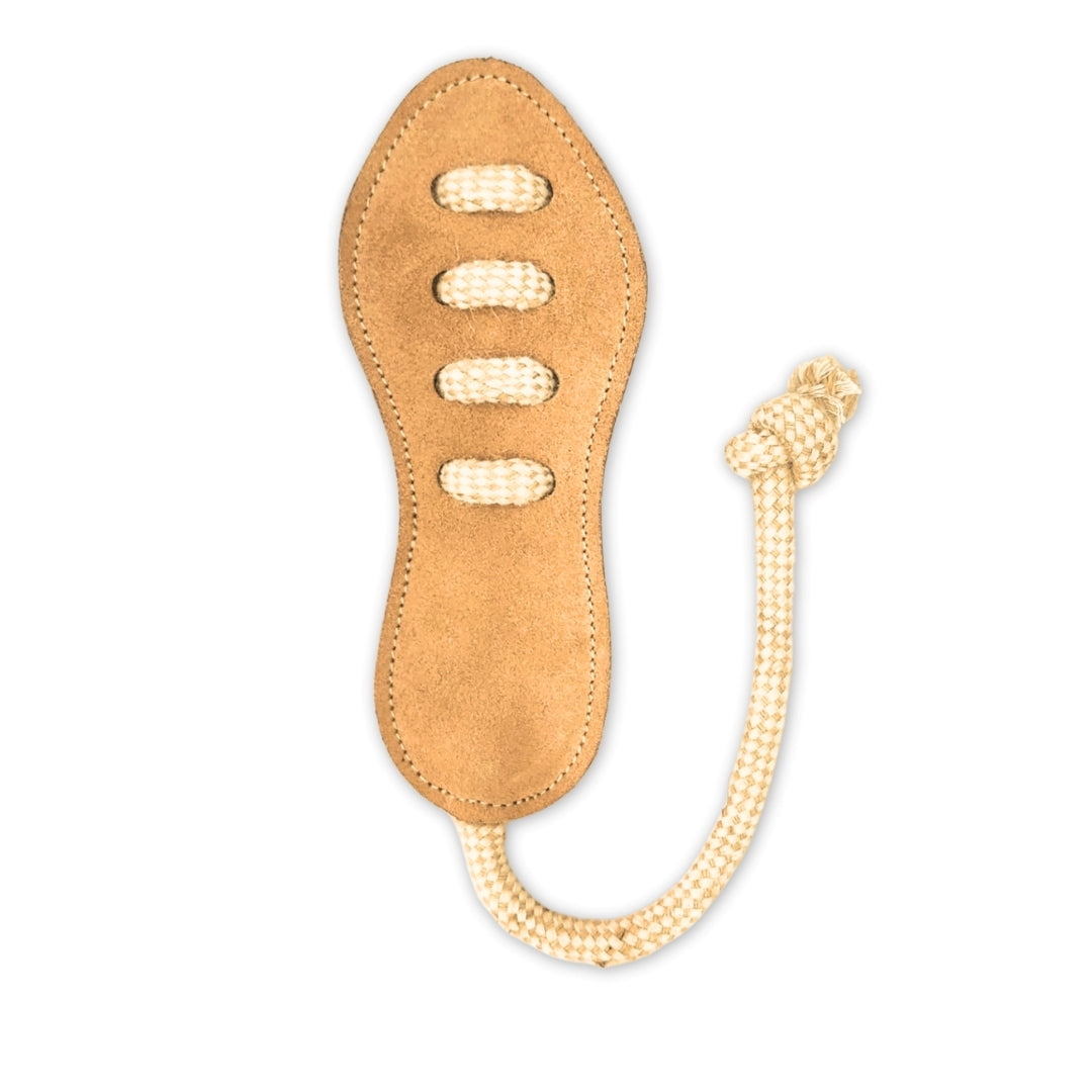 A tan buffalo leather Footy Boot - raw lash whip from Georgie Paws with an intricate handle design resembling a shoe sole, featuring white threads in patterns similar to shoe laces, attached to a white braided rope. The background is plain white.