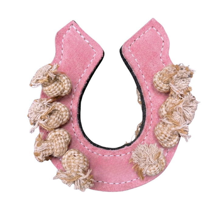 A pink, horseshoe-shaped fabric ornament with white stitching and seven beige knotted tassels attached to one side. Crafted with a black backing, this handcrafted decorative piece features natural materials for an eco-friendly touch.