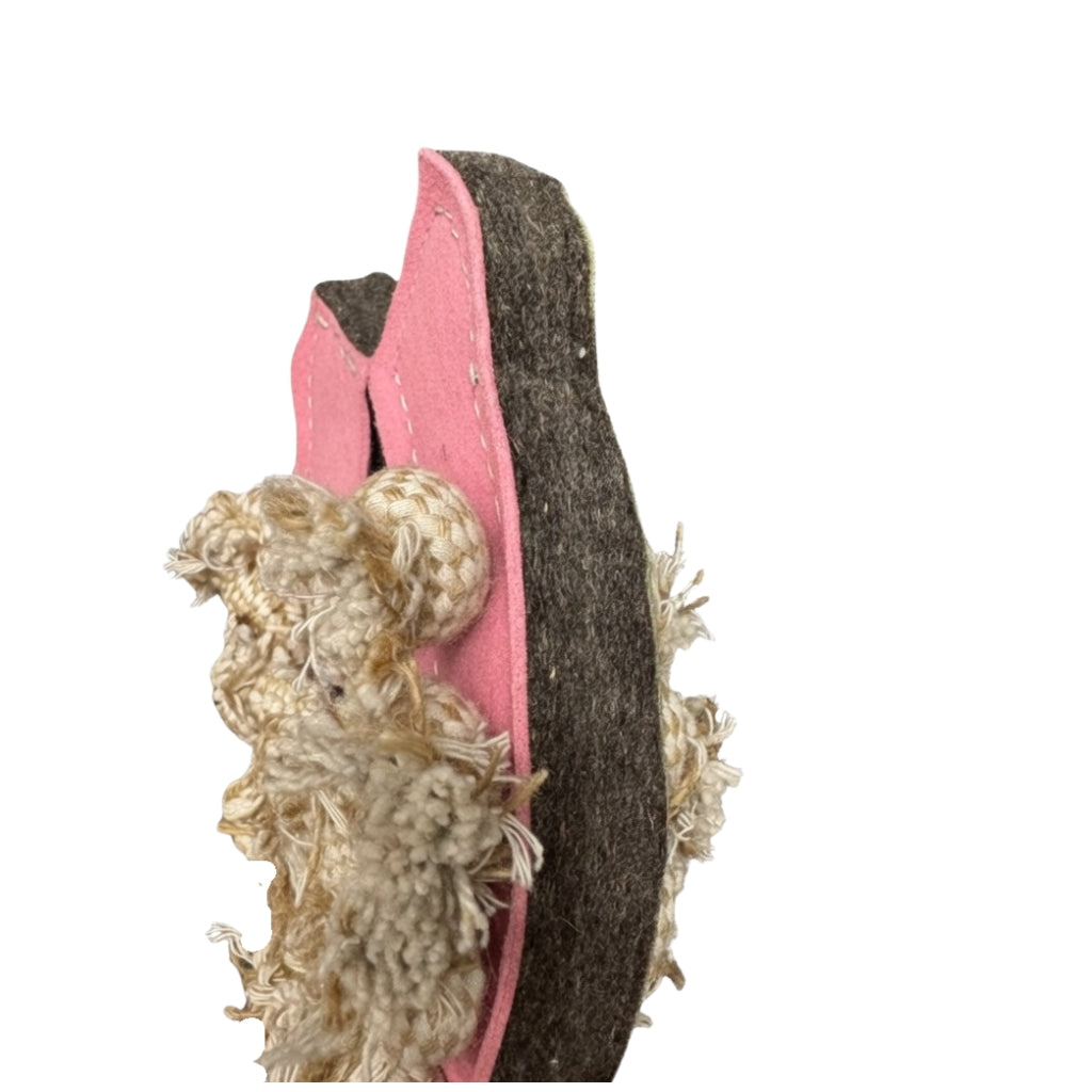 A sustainable dog toy shaped like a pink sandal with frayed rope attached, suggesting wear from chewing. The toy appears worn and textured, with visible stitching and stuffing coming out on one side, isolated on a white background.