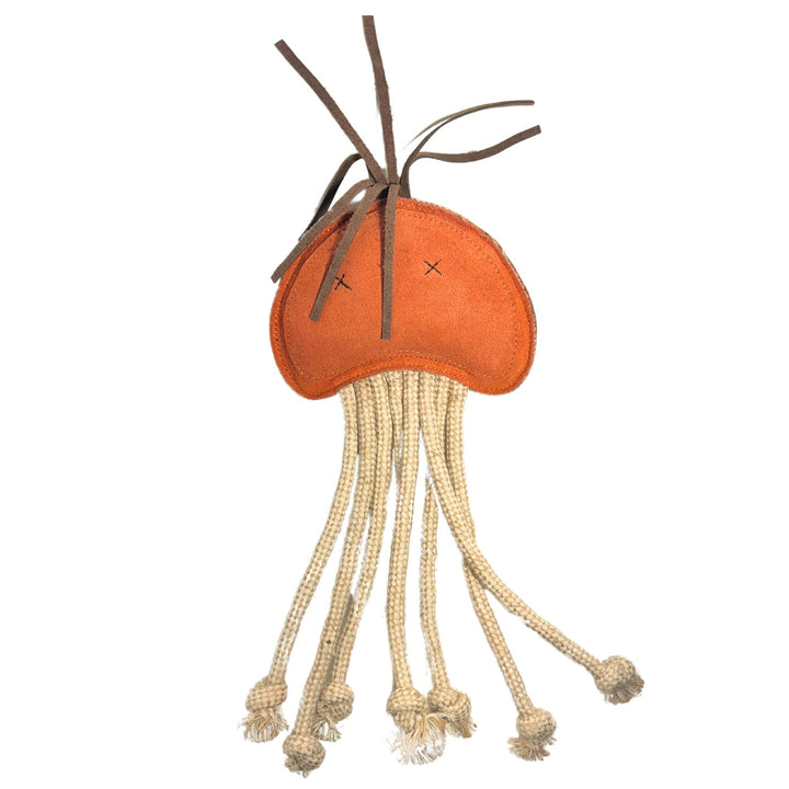 A plush orange jellyfish toy with a stitched face featuring two X eyes. Long, cream-colored rope tentacles hang from the bottom, some ending in knots. Brown strings resembling tendrils stick out from the top. Crafted using sustainable materials, it offers a natural charm against a plain white background.