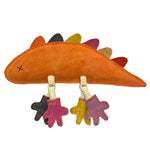 Introducing Larry Lizard - rainbow from Georgie Paws, a dinosaur fabric toy meticulously crafted from eco-friendly orange felt. This delightful toy features a vibrant row of multicolored felt spikes running down its back and stitched eyes for an added touch of charm. Its hanging legs are made from cream-colored cords, each ending in small felt feet available in black, purple, yellow, and pink hues. The visible stitching enhances its endearing handmade appearance.