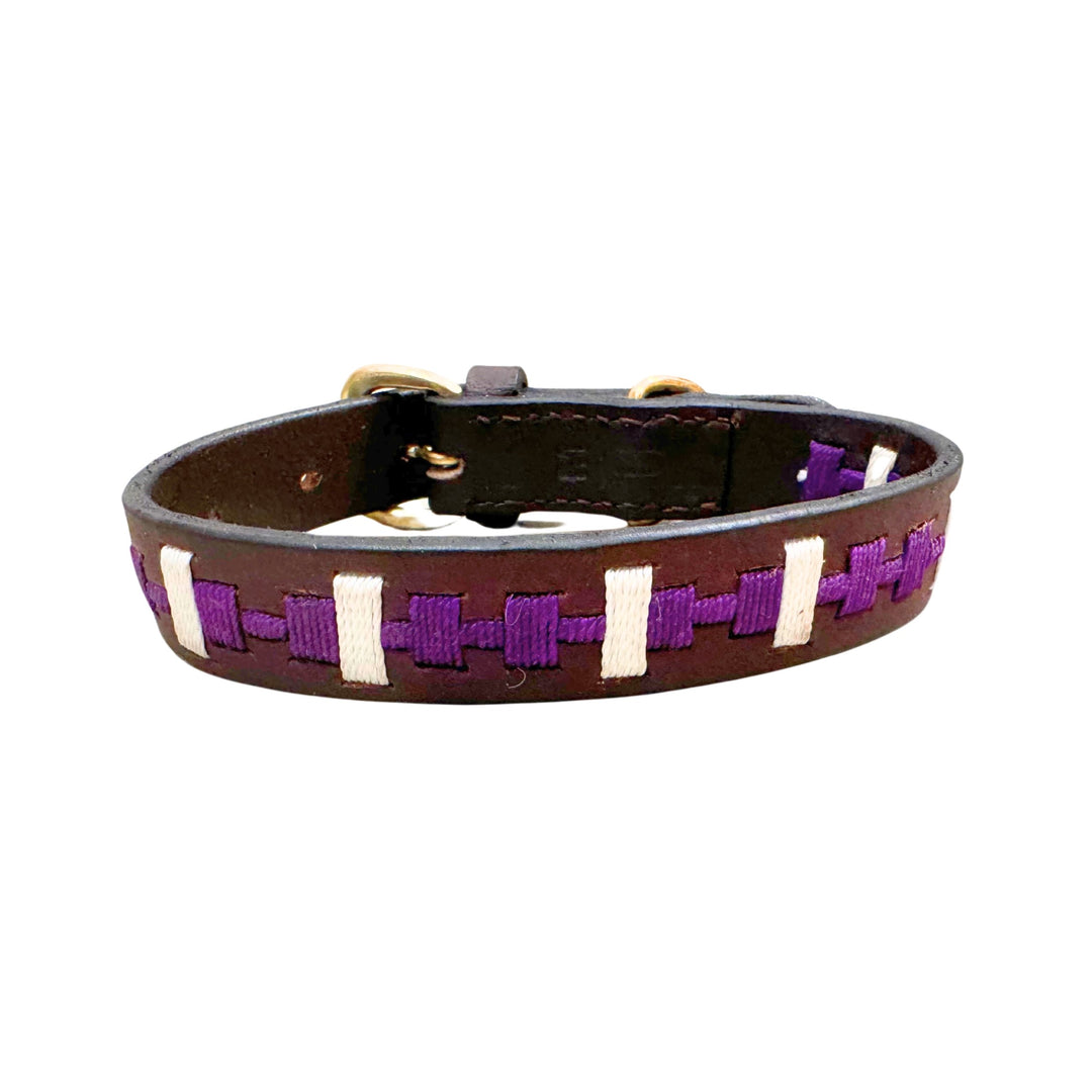 Introducing the Polo Collar - Lokki purple by Georgie Paws, a striking accessory crafted from premium buffalo leather. This woven design features purple and white threads, complemented by a metallic buckle for an adjustable fit. Laid flat on a white background, its intricate pattern echoes the craftsmanship of Georgie Paws’ distinctive accessories.