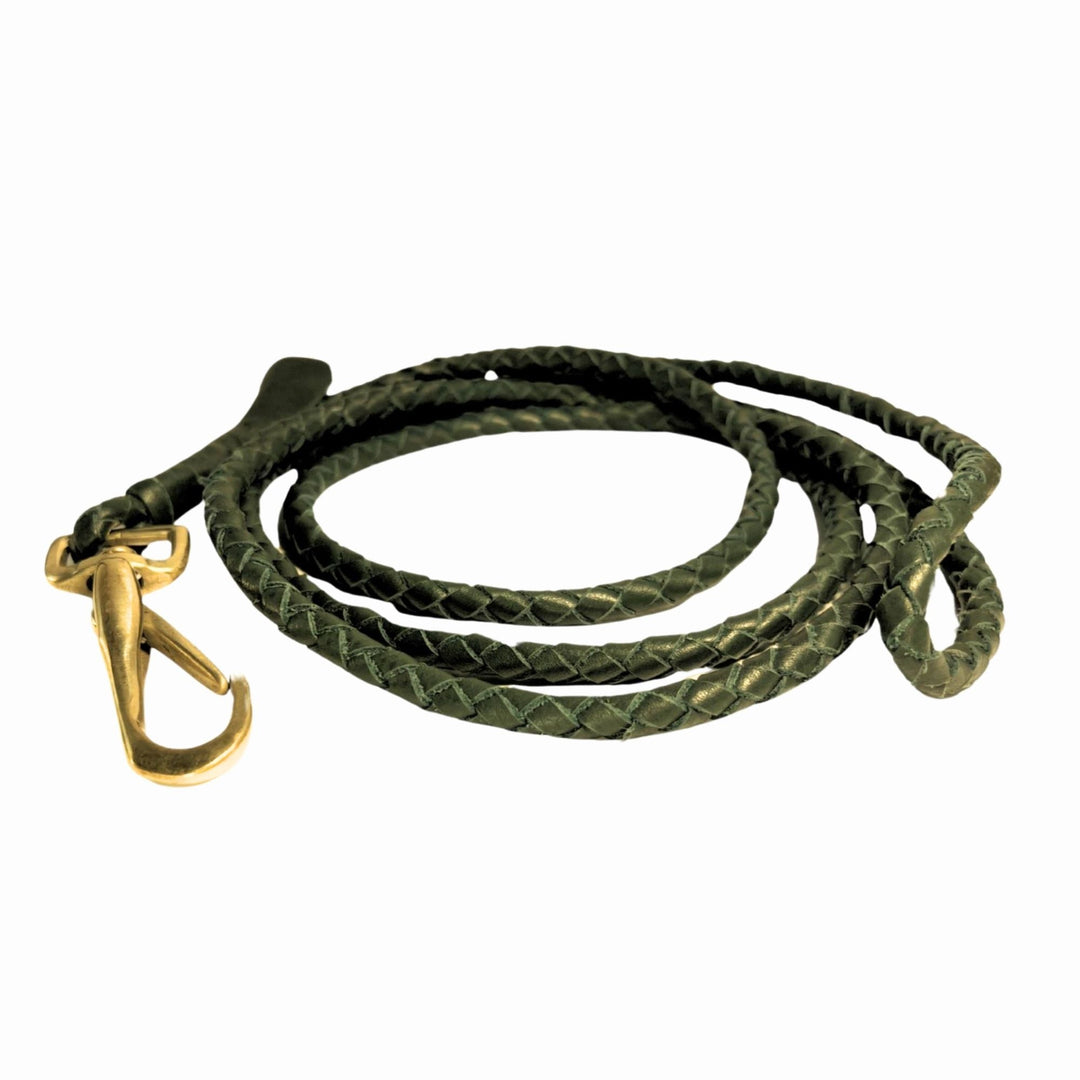 The LuLu Lead - Chive by Georgie Paws is displayed on a white background, neatly coiled in a spiral. This dark green braided leather dog leash features a handmade texture and is finished with a gleaming brass clasp.
