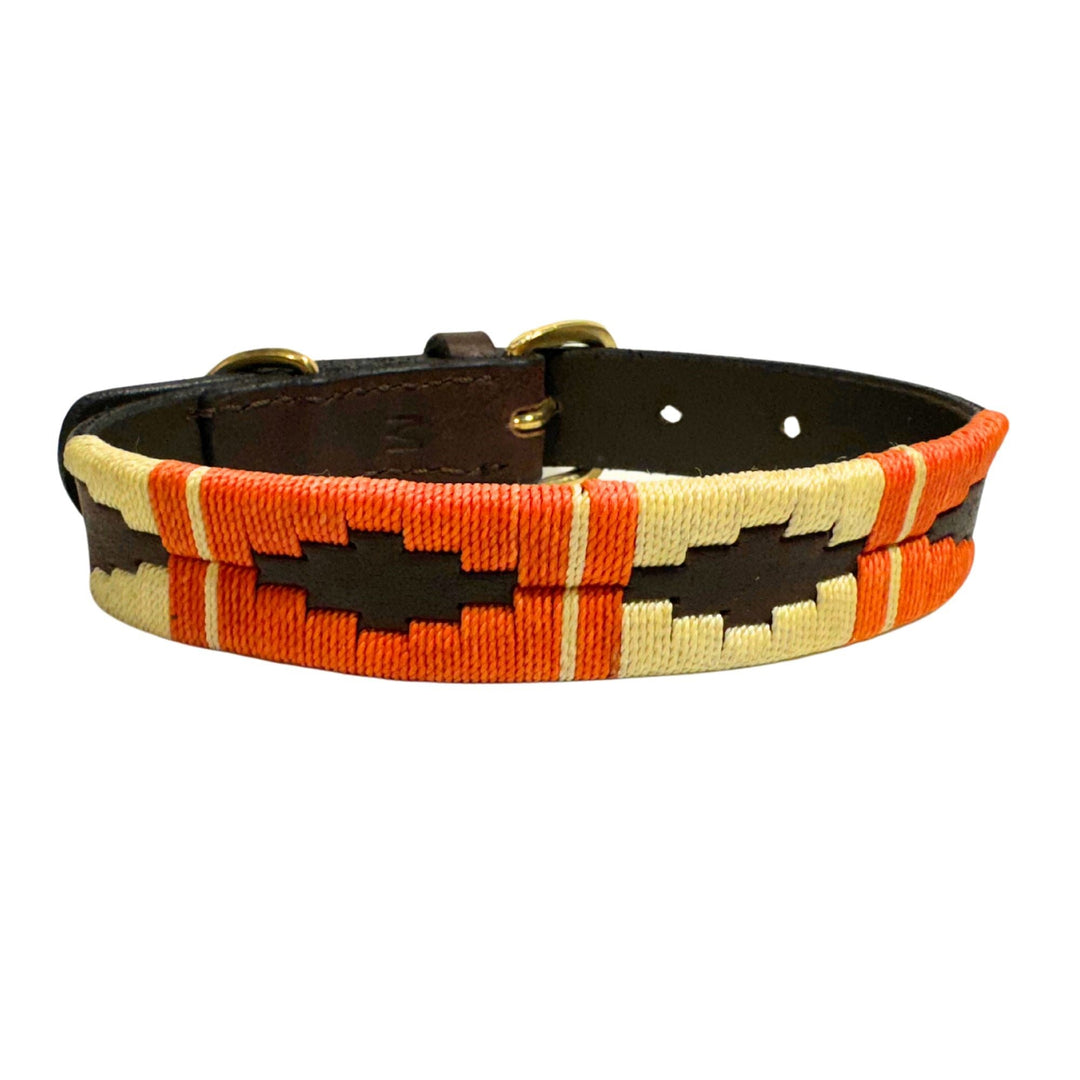 The Georgie Paws Polo Collar - Angus is a brown vegetable tanned buffalo leather dog collar featuring orange, cream, and yellow woven geometric patterns and gold metal hardware; the collar is shown lying flat with fastening holes visible.