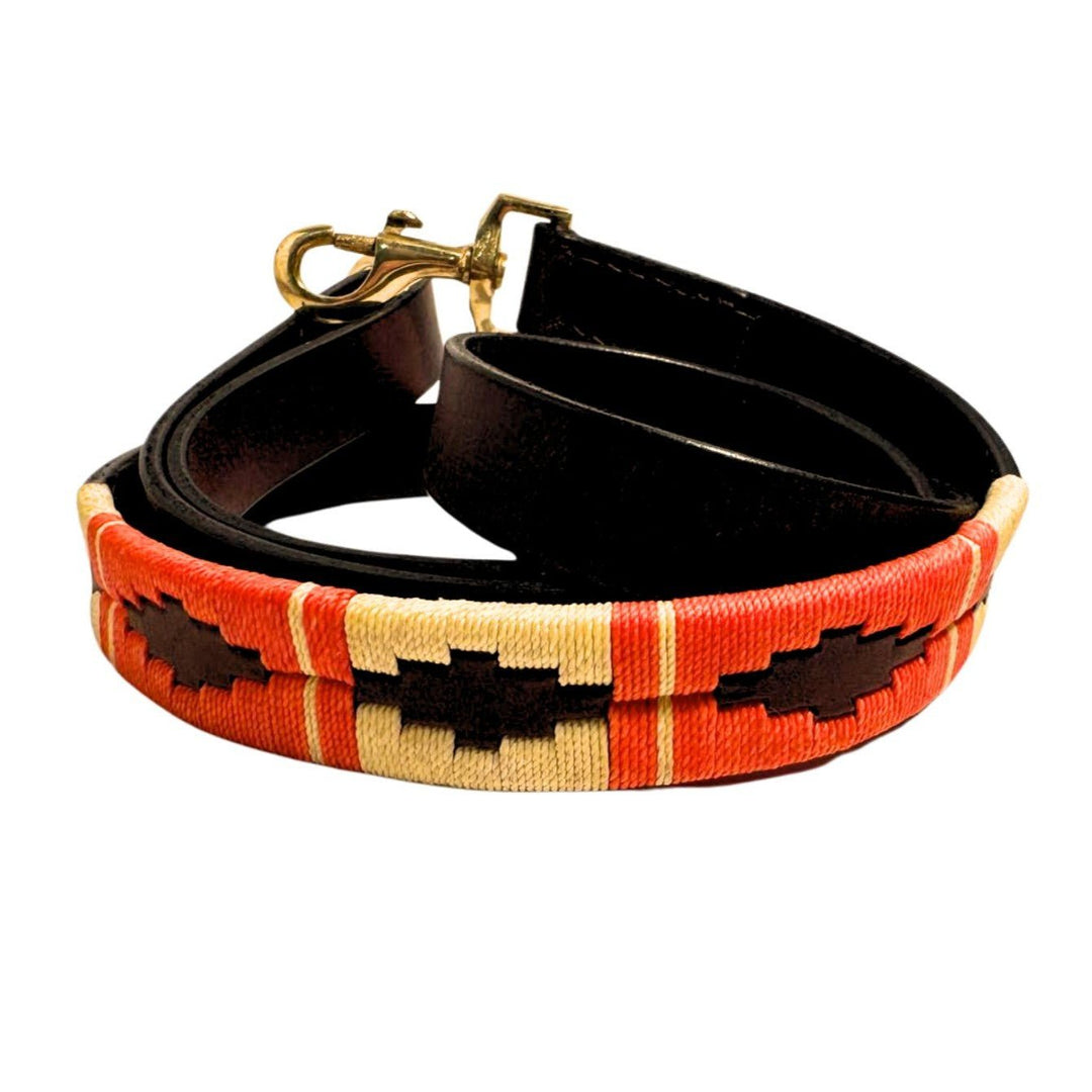 Introducing the Polo Lead - Angus by Georgie Paws: a handmade rolled black leather dog leash crafted from vegetable tanned buffalo leather. This leash features a distinctive stitched fabric section in red, cream, and brown with a geometric pattern, adding decorative flair. The brass clasp and detailed stitching are clearly visible for both style and durability.