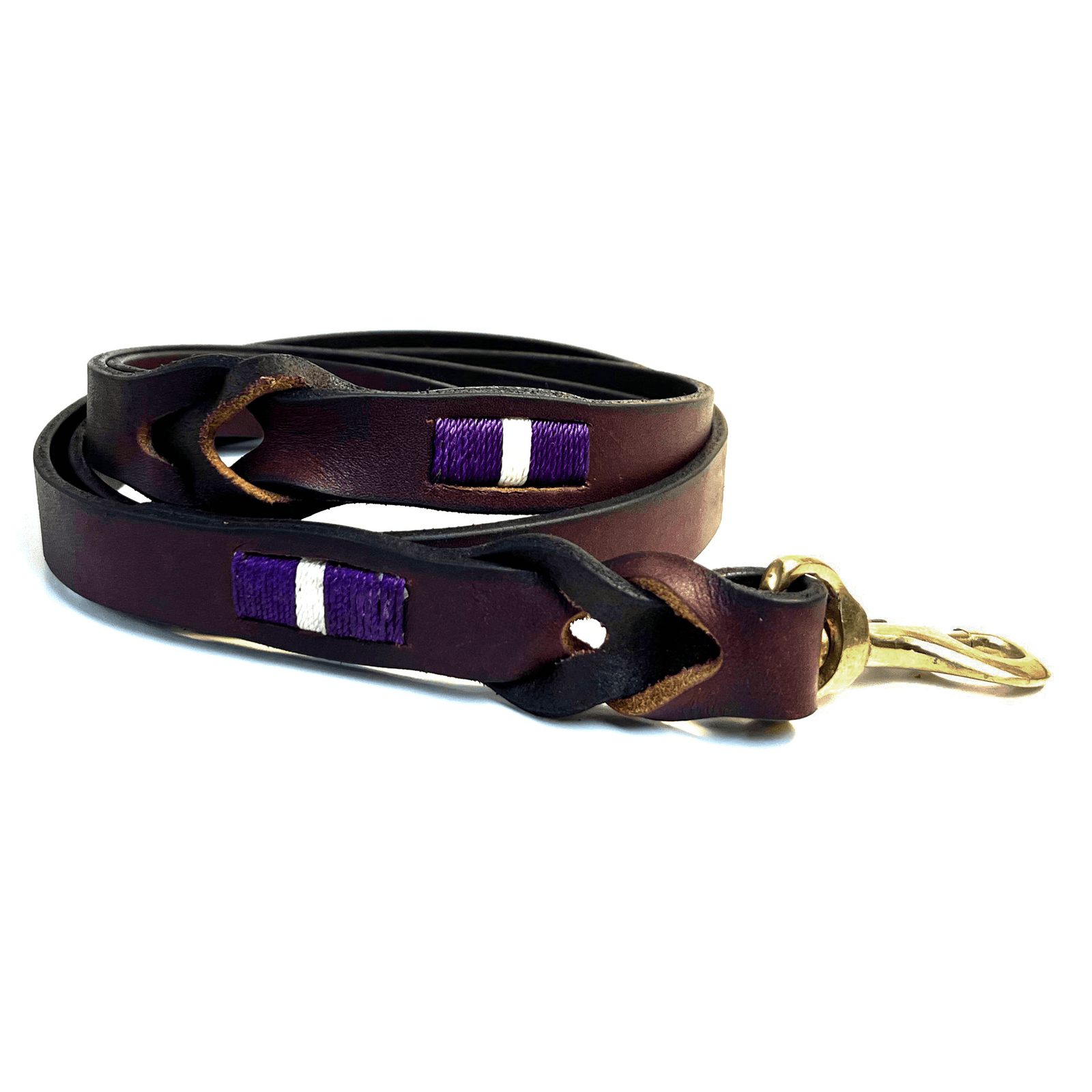 The Polo Lead Locker - Purple by Georgie Paws is a brown, vegetable-tanned buffalo leather leash with a brass clasp, coiled neatly. It showcases decorative purple bands accented with a central white stripe, stitched in two places along its length. The natural leather edges display slight wear, highlighting its quality craftsmanship or previous use.