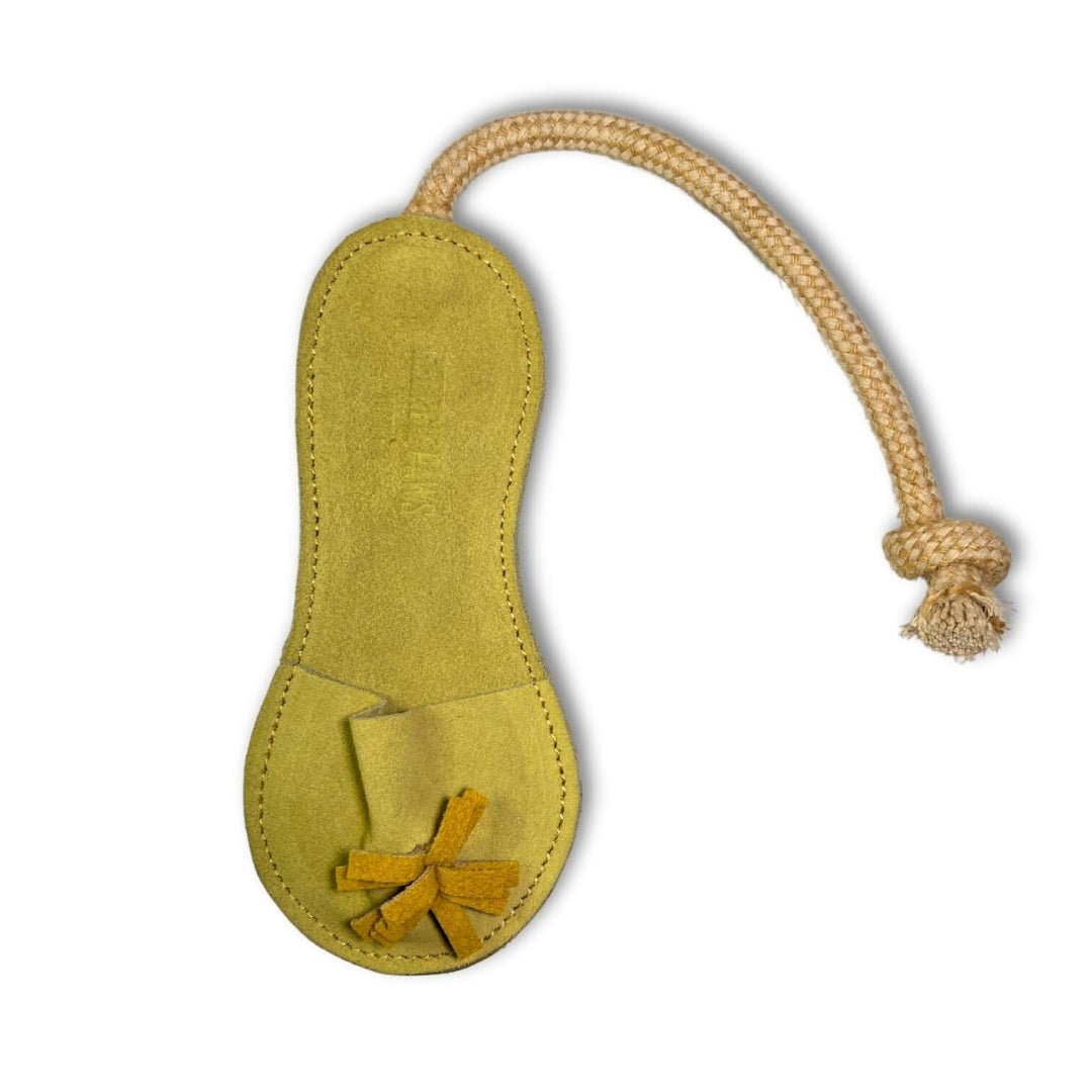 Introducing the Sigrid Slipper - Pear by Georgie Paws: a yellow-green, handmade suede cat toy crafted to resemble a shoe, with visible stitching and natural vegetable tanned buffalo leather. A small pocket at the toe holds criss-crossed suede strips, while a tan rope attached at the heel ends in a tight knot. The product is photographed against a plain white background.