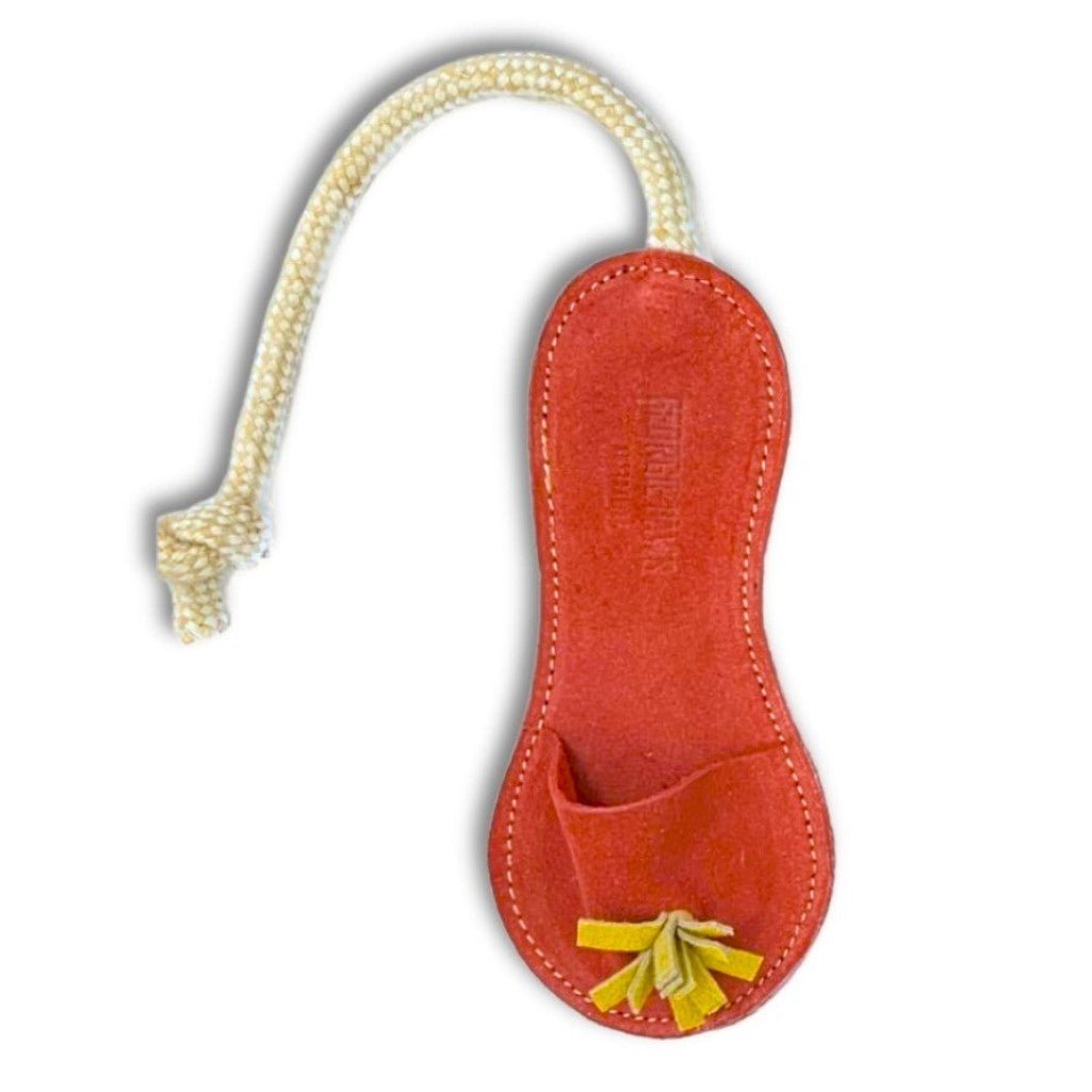 Introducing the Sigrid Slipper - Red by Georgie Paws: a handmade keychain crafted from vegetable tanned buffalo leather and shaped like a peanut. It features vibrant red leather with visible stitching, accented by cheerful yellow tassels, a small front pocket, and sturdy white rope attached. Embossed text adds a refined touch to this unique accessory, beautifully photographed against a plain white background.