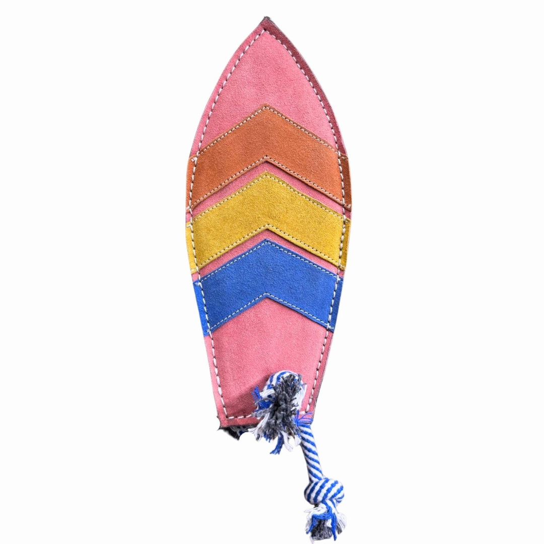 The Georgie Paws Surfboard Dog Toy features a leaf shape in Buffalo Suede with chevron patterns in brown, orange, yellow, and blue, white edge stitching, and a blue-and-white rope at the bottom. A sustainable toy shown on a white background.