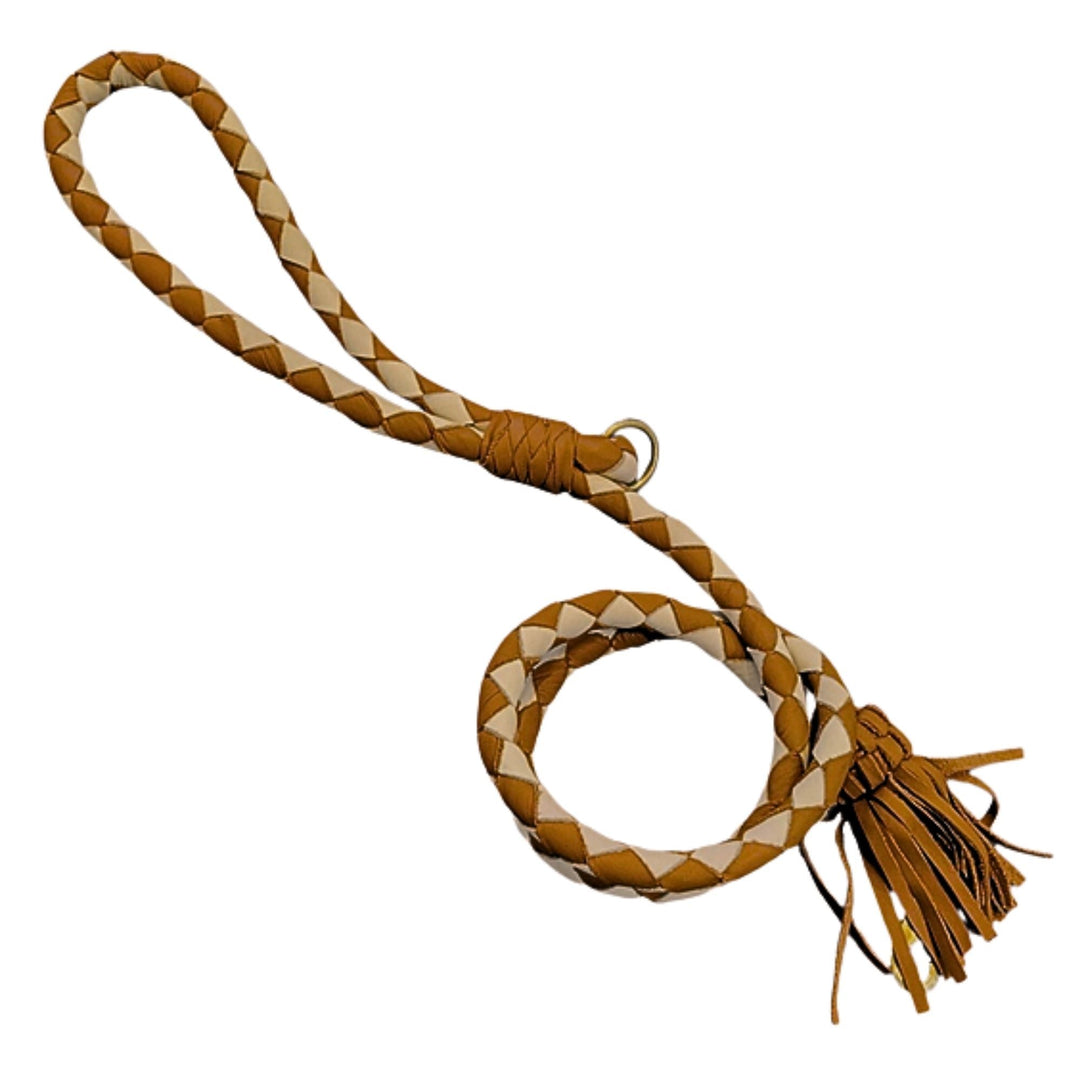 Introducing the Swanky Lead - Syrup by Georgie Paws: a handcrafted braided leather lead featuring a loop handle and fringed tassels at one end. This stylish lead displays alternating tan and light beige segments for an eye-catching pattern along its length, complemented by a thicker handle ending in a sturdy metal ring to highlight its natural materials.