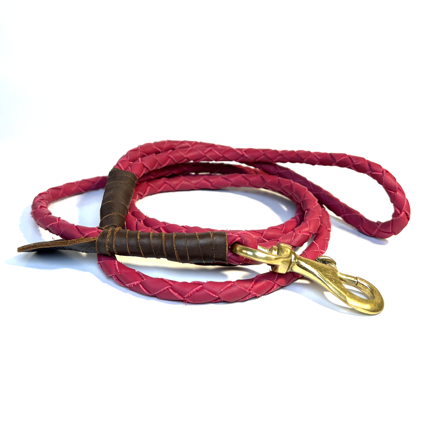 The Windsor Lead - Ruby by Georgie Paws is a handmade, coiled red leather braided dog leash crafted from premium buffalo leather. It features antique brass hardware and brown leather detailing near the securely attached clasp, and is displayed on a white background.