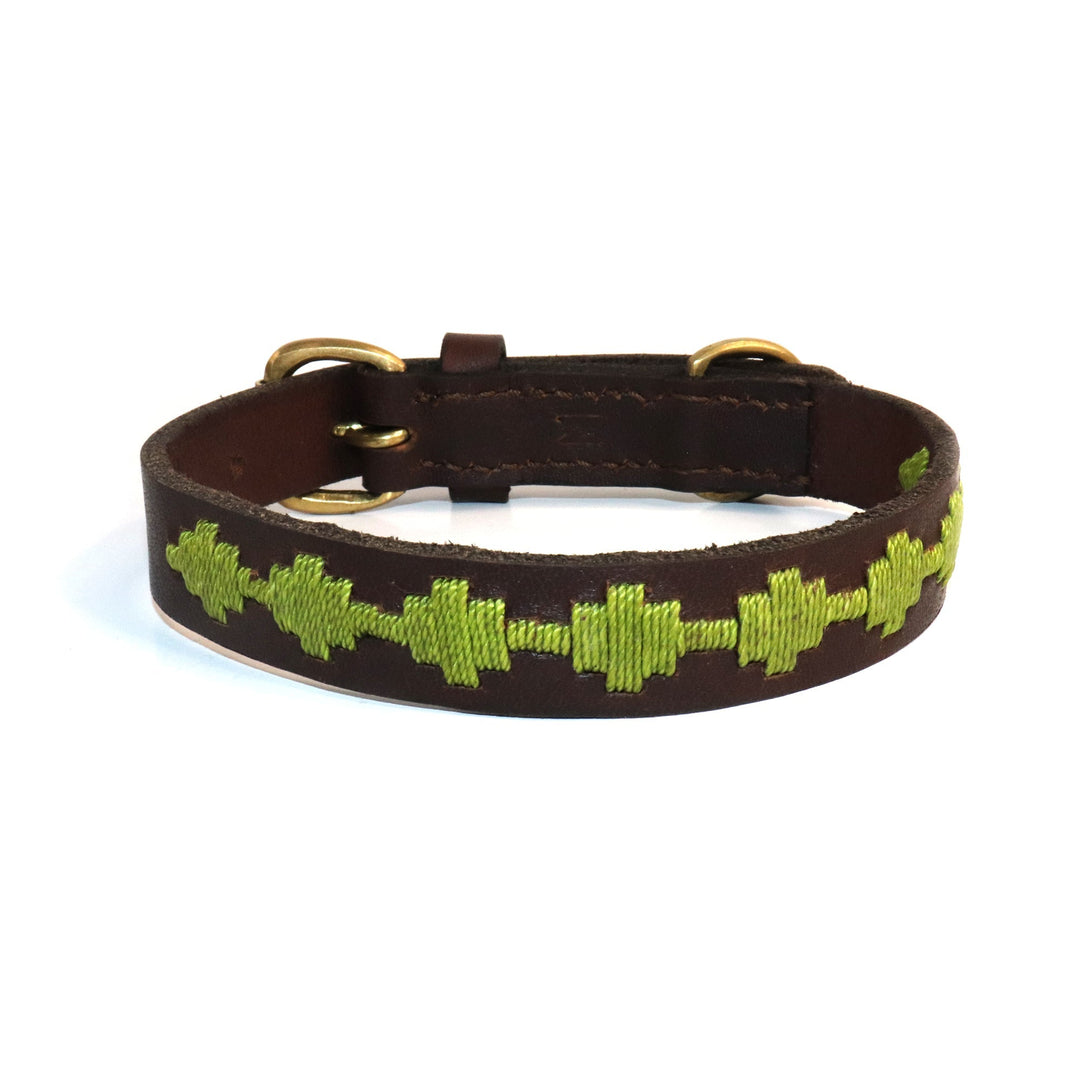 Introducing the Polo Bark Collar - Grass by Georgie Paws: a handmade brown vegetable tanned buffalo leather collar adorned with a stitched pattern of green cross shapes along its length. This collar features two gold-colored metal rings for fastening and adjustment, and is artfully displayed against a white background.